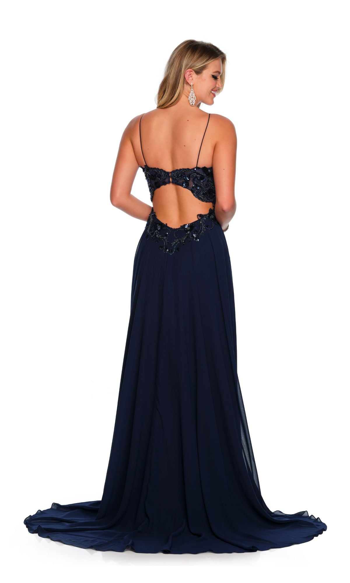 A woman models the Dave and Johnny Navy Blue Long Formal Dress 11241, featuring thin straps, floral detailing, and an open back, against a white background.